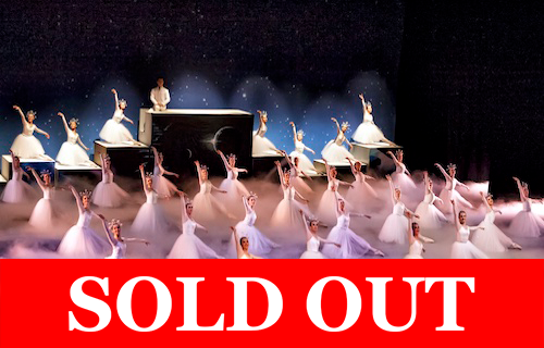 Stage performance of ballet dancers in white costumes with a large red “Sold Out” banner across the bottom.