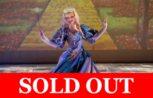 Performer dressed as a princess in a sparkling gown holding a wand on stage, with ‘SOLD OUT’ banner across the bottom.